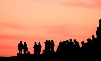 Silhouettes of people with different expressions on the embankment of the sea sunset.