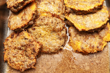 Several fried cutlets in egg batter in oil, top view.