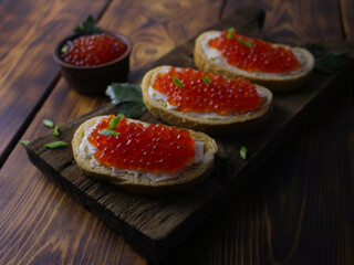 sandwiches with red caviar on a wooden tray