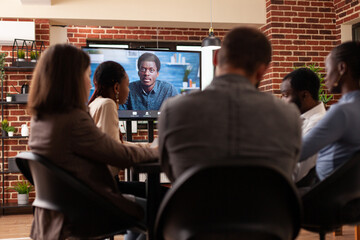 Obraz premium Diverse people discussing management partnership with remote manager during online videocall meeting working at company presentation in startup office. Business call conference on monitor
