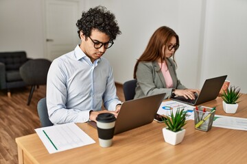 Two business workers with serious expresison working using laptop at the office.