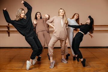 Group of girls in sportswear, performing elements of house dance in a dance studio, dancing with pleasure. The concept of sports youth