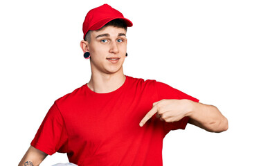 Young caucasian boy with ears dilation wearing delivery uniform and cap holding bike helmet smiling...