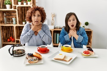 Family of mother and down syndrome daughter sitting at home eating breakfast shouting and suffocate because painful strangle. health problem. asphyxiate and suicide concept.