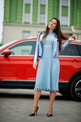 Outdoor photo of gorgeous woman posing near orange suv car.