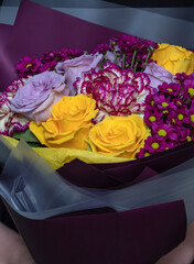 Bouquet of yellow and purple roses, pink carnations and chrysanthemums. An image for a flower shop, a postcard. Selective focus.