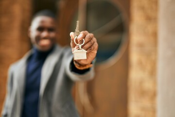 Obraz premium Young african american man smiling happy holding new home key at the city