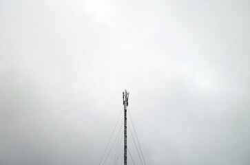 Telecommunication tower or mast against grey sky.