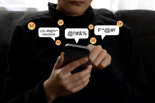 Teen mental health problem, social media harassment concept. A preteen schoolboy, teenager using smartphone alone feeling frustrated after reading bad comments, text negative emoticons.