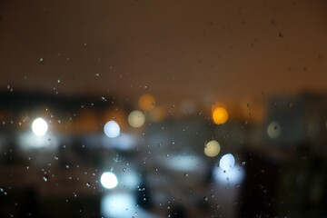 Obraz na płótnie Canvas View from window with rain drops on night city.