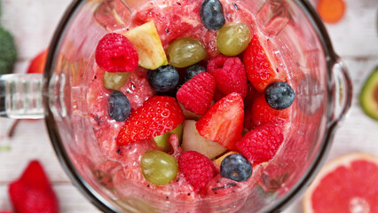 Mixing pieces of fruits in blender, top view.