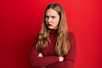 Young blonde woman wearing turtleneck sweater skeptic and nervous, disapproving expression on face with crossed arms. negative person.