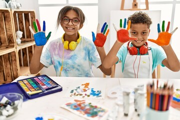 Brother and sister wearing headphones showing painted palm hands at art studio