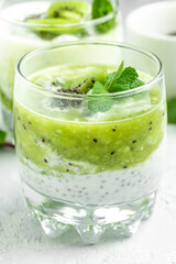 Healthy breakfast chia pudding with kiwi in glass jars on a white table. Clean eating, dieting, vegan food concept. vertical image
