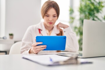 Young blonde woman wearing doctor uniform using touchpad working at clinic