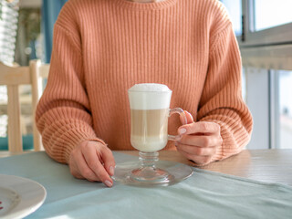 Lunch break for coffee. Woman sitting at the table in a cafe, drinking latte. Closeup image concept.