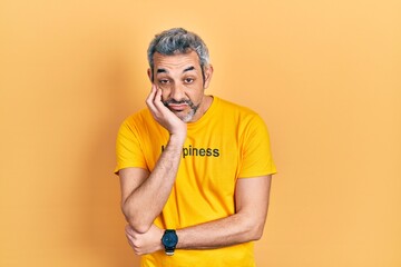 Handsome middle age man with grey hair wearing t shirt with happiness word message thinking looking tired and bored with depression problems with crossed arms.