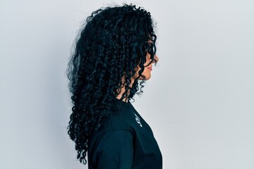 Young hispanic woman with curly hair wearing staff t shirt looking to side, relax profile pose with natural face and confident smile.