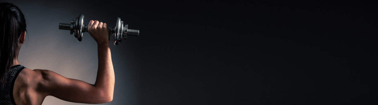 Beautiful young woman workout with dumbbell over gray background in fitness gym club