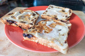 Buttered, toasted fruit loaf on a plate is comfort food eaten for breakfast or as tasty snack.