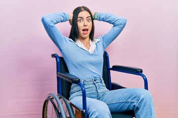 Obraz premium Beautiful woman with blue eyes sitting on wheelchair crazy and scared with hands on head, afraid and surprised of shock with open mouth