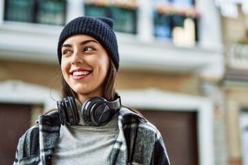 Young hispanic woman smiling happy using headphones at the city.