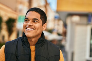 Young latin man smiling happy standing at the city