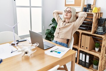 Young caucasian woman smiling confident relaxed with hands on head at office