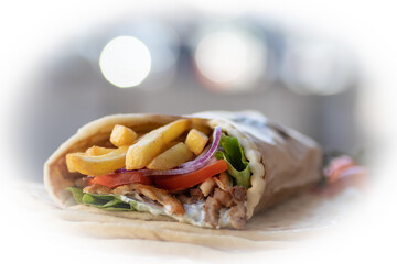 Greek Gyros street food for take away, nicely wrapped with tomato, souvlaki, Greek salad, onion and French fries  