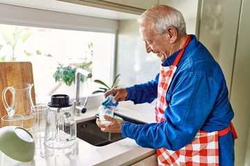 Fototapeta na wymiar Senior man smiling confident washing glass at kitchen