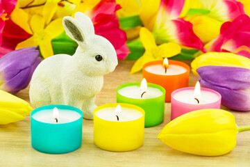 Bunte Dekoration für Ostern mit Osterhase, Tulpen und Kerzen auf Holz