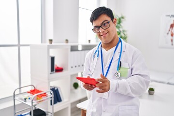 Down syndrome man wearing doctor uniform using touchpad at clinic