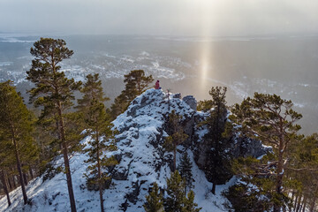 A tourist sits on top of a cliff and admires the views