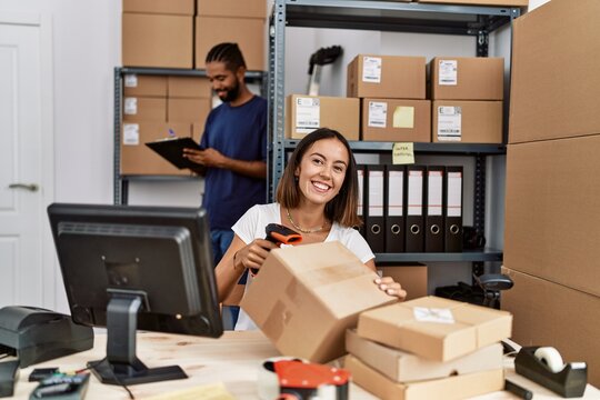 Man and woman business partners scanning package using barcode reader at storehouse