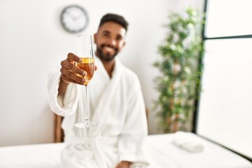 Young african american man relaxed smiling happy drinking champagne at beauty center.