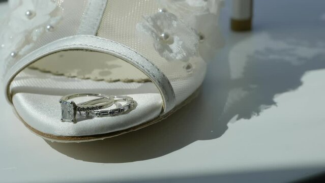 Close up wedding rings on tip of wedding shoes