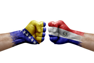 Two hands punch to each others on white background. Country flags painted fists, conflict crisis concept between bosnia and paraguay