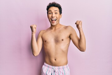 Fototapeta premium Young handsome man wearing swimwear shirtless celebrating surprised and amazed for success with arms raised and open eyes. winner concept.