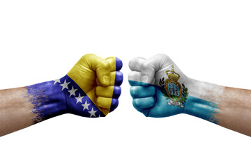 Two hands punch to each others on white background. Country flags painted fists, conflict crisis concept between bosnia and san marino