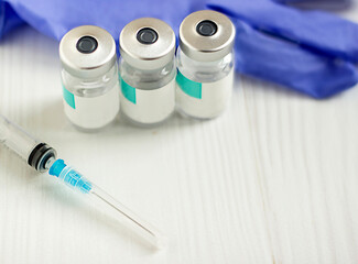 syringe and ampoules, blue medical gloves in the background