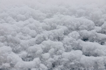 Beautiful winter background with snowy ground. Natural snow texture. Wind sculpted patterns on snow surface
