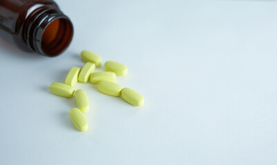 vitamins for women yellow capsules on a white background with an open bottle