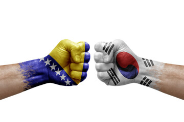 Two hands punch to each others on white background. Country flags painted fists, conflict crisis concept between bosnia and south korea