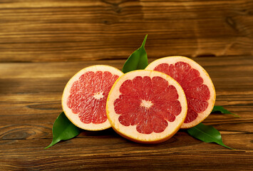 Fototapeta na wymiar cut grapefruit on a wooden background with green leaves