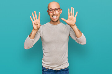 Bald man with beard wearing casual clothes and glasses showing and pointing up with fingers number nine while smiling confident and happy.