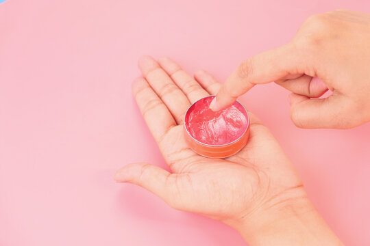 woman using petroleum jelly on pink background