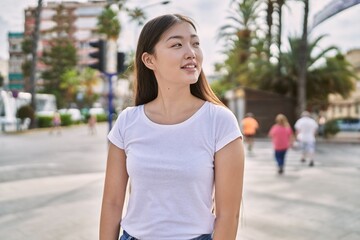 Young chinese girl smiling happy standing at the city.