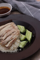 Hainanese chicken rice served with dipping sauce on a wooden table.