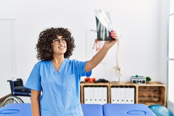 Young middle east woman wearing physio therapist uniform holding xray at clinic