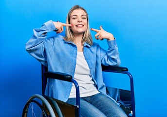 Beautiful caucasian woman sitting on wheelchair smiling cheerful showing and pointing with fingers teeth and mouth. dental health concept.